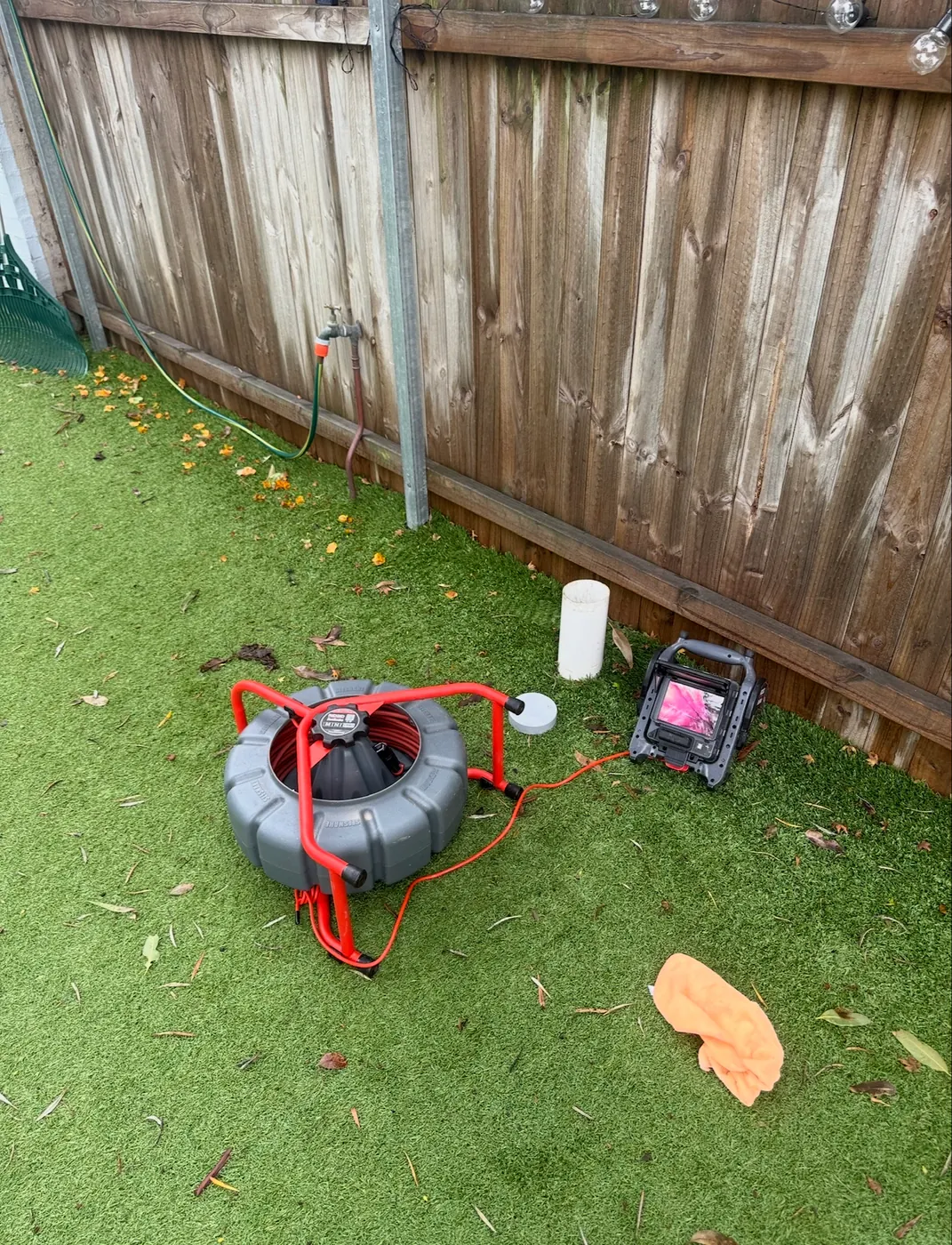 Drain camera reel and monitor set up at a drain in a backyard