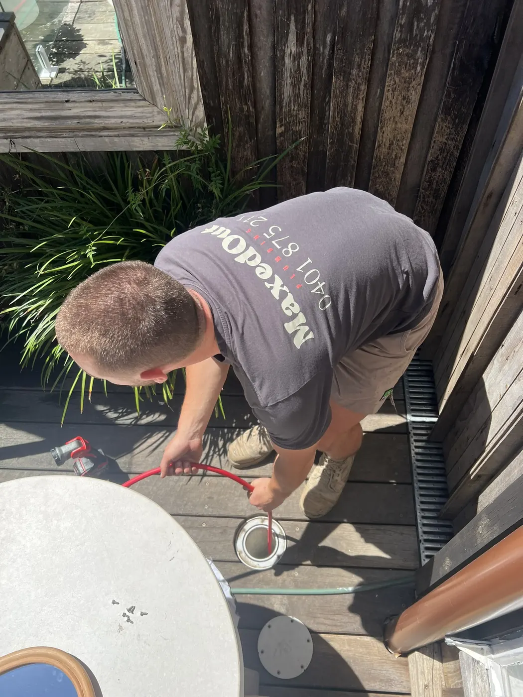 MaxedOut plumber taping a fitting on a timber deck