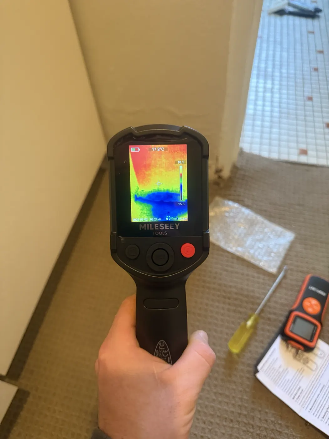 Thermal camera showing a cold patch on a bathroom floor, with a moisture meter