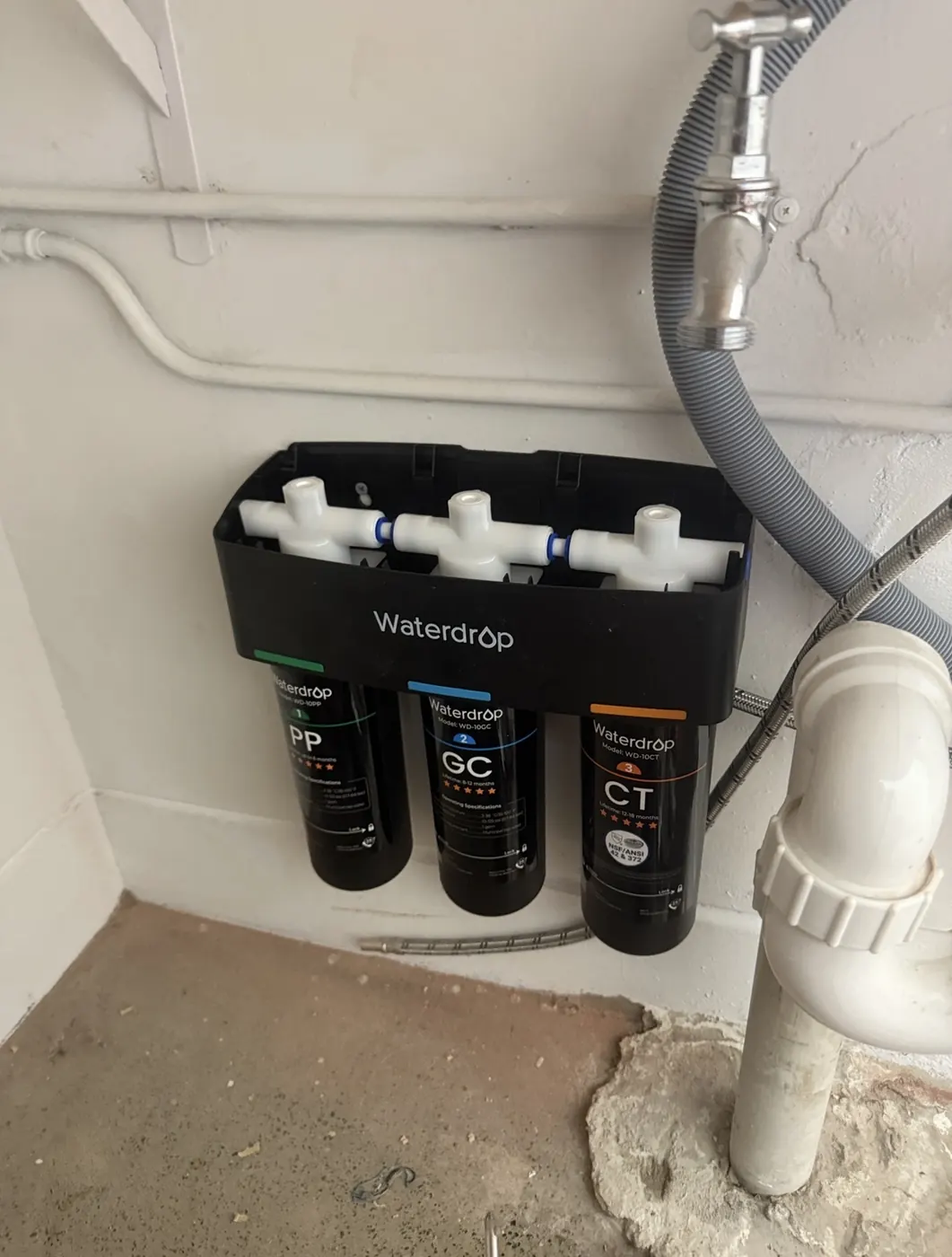 Three-stage water filter installed in a cupboard under a sink