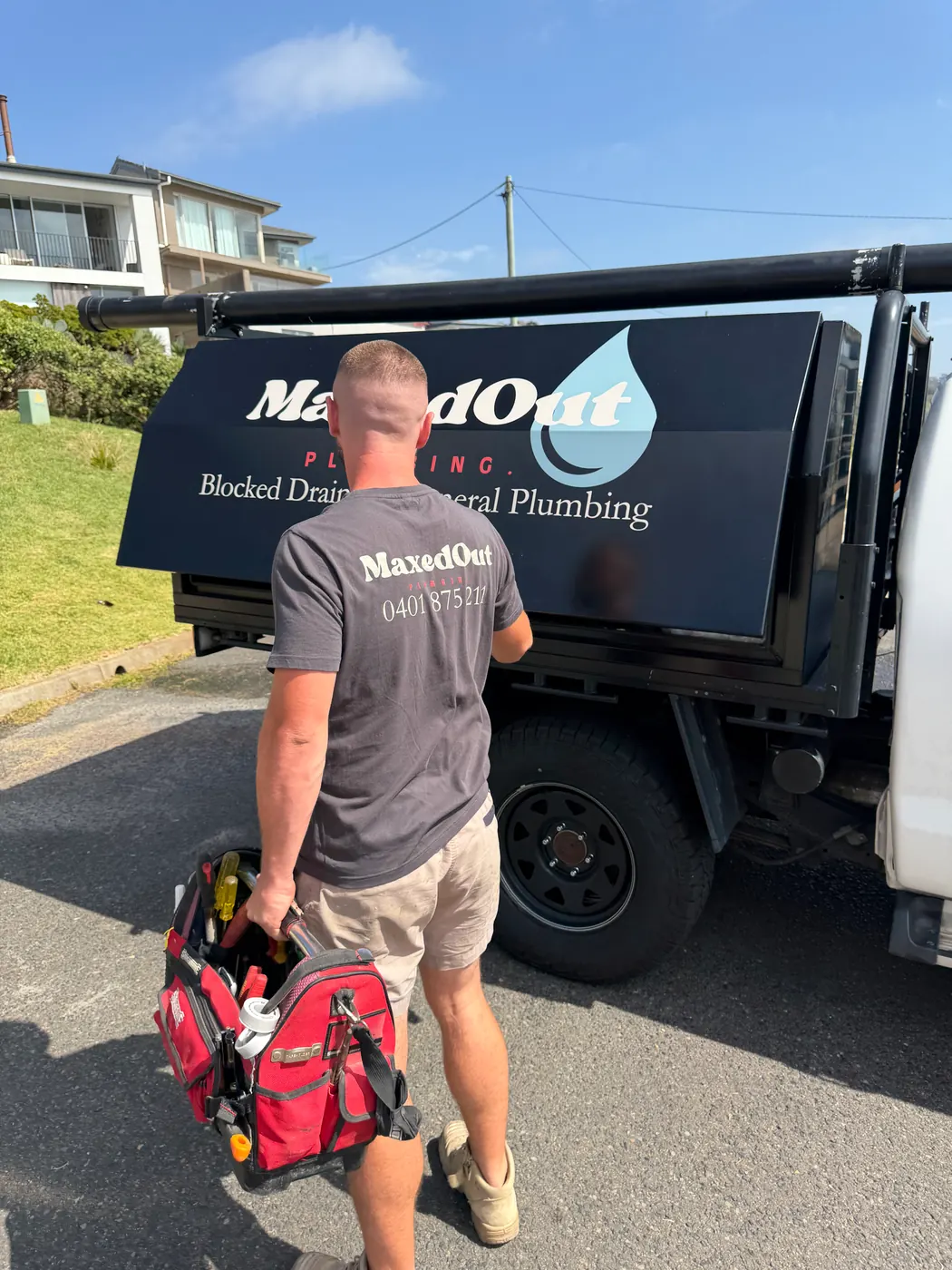 MaxedOut plumber carrying a tool bag to the signwritten ute